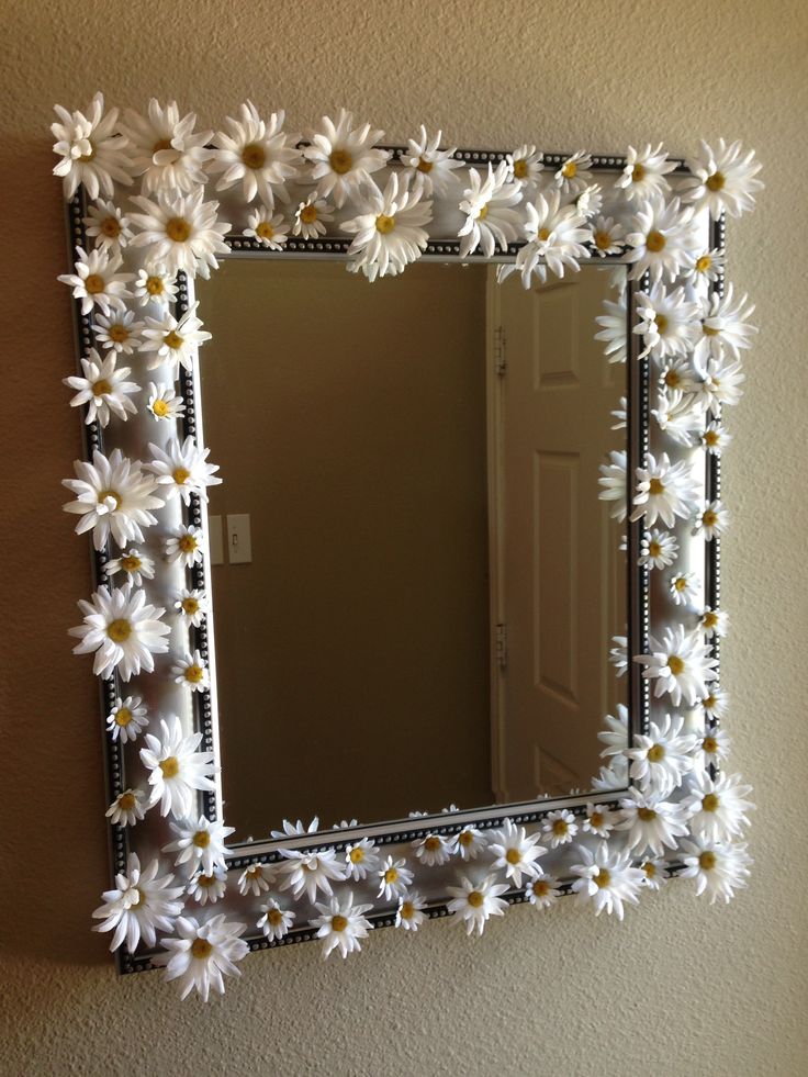 a mirror that has flowers on it and is hanging on the side of a wall