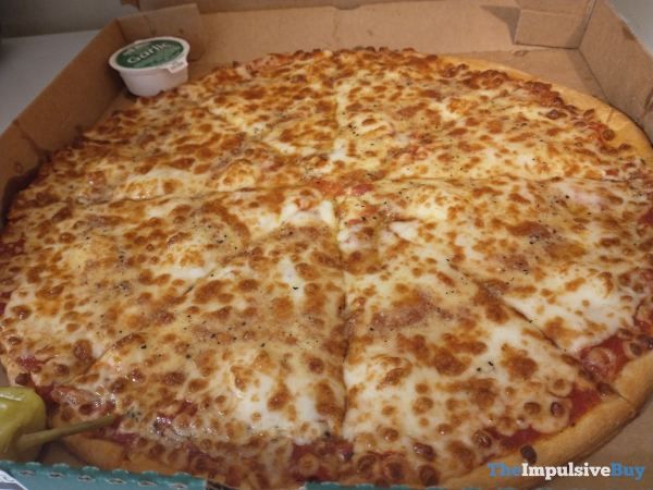 a large pizza sitting in a box on top of a counter next to a pickle