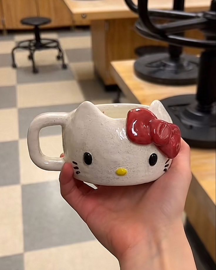 a person holding a hello kitty mug in their hand