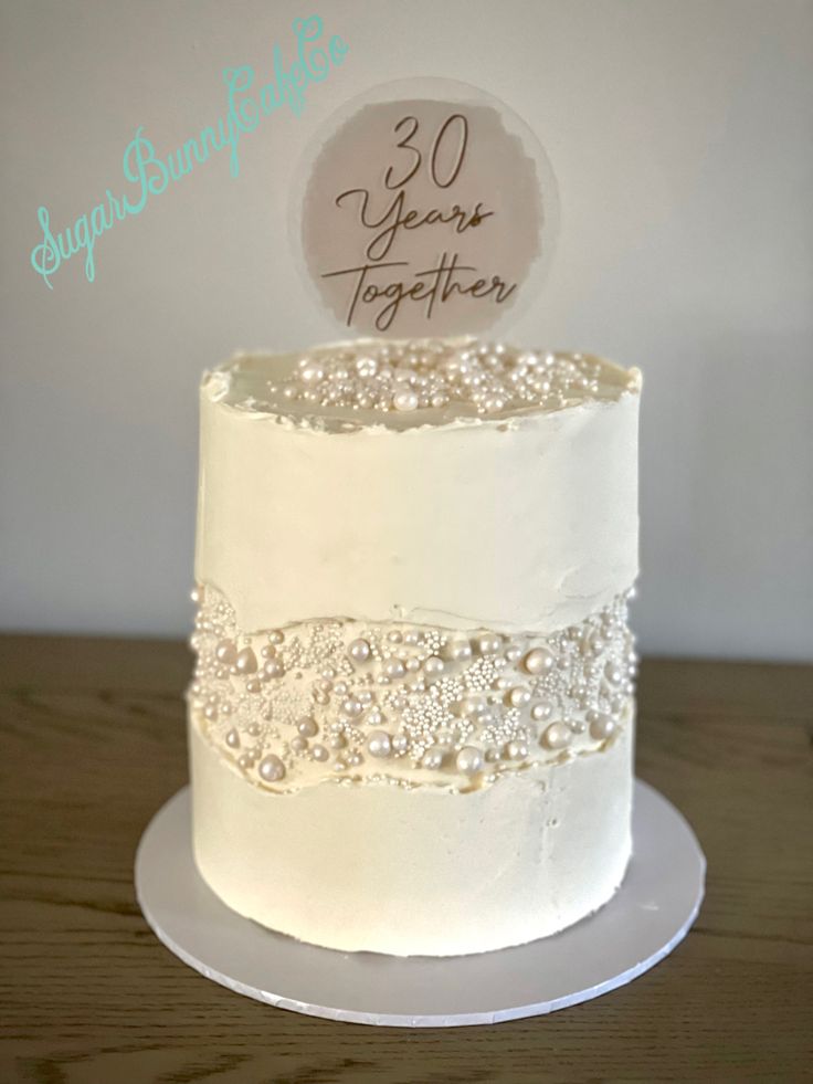 a white wedding cake with pearls and a 30 year together sign on it's side