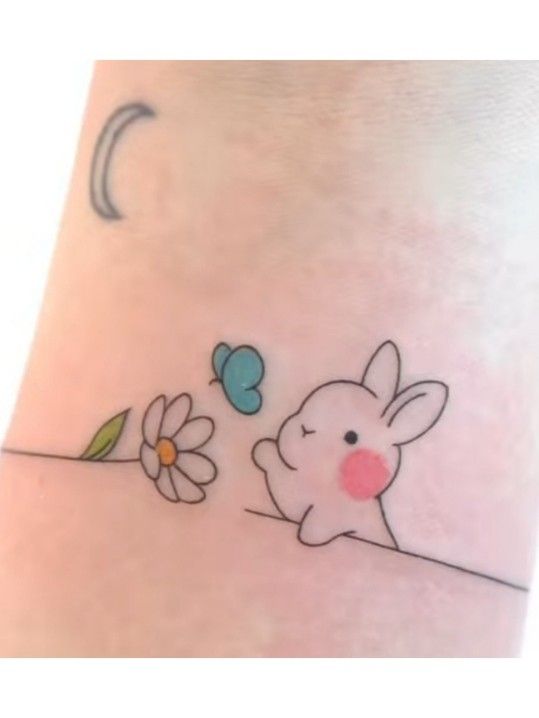 a small bunny and flower tattoo on the ankle