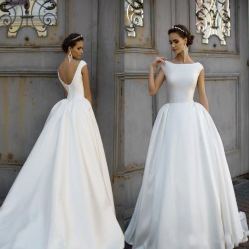 two women in wedding dresses standing next to each other, one wearing a white dress