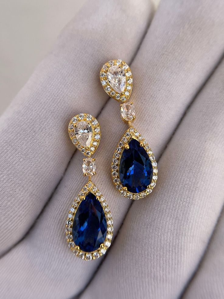 Luxury Blue Sapphire Earrings, Tear Drop Earrings, Pear Cut Earrings, Halo Earrings, 14k Solid Gold, Wedding Earrings, Engagement Earrings Handmade earring. Stone : Lab Blue Sapphire Gemstone Cut : Pear Cut Side Stone : Cubic Zirconia Metal  : 14k Gold / 925 Silver Plating : Platinum/Gold/Rose Gold Personalization: 10K/14K/24K/GOLD/SILVER/PLATINUM/ROSE-GOLD/WHITE GOLD. (Contact me)  All items come in a beautiful jewelry box.  Since all out Jewelry is Handmade with care and love, It takes [6-8 Business Days] to make the item. Once the item is made: Standard Shipping: 1-3 Weeks Express Shipping: 4-12 Days.  If you need anything personalized then you are MOST WELCOME. We specialized in personalized jewelry of all kinds, We have All Gemstones available as well as all Metals including White Gol Gold Sapphire Earrings, Luxury Blue Pear-shaped Earrings, Exquisite Teardrop Bridal Earrings For Formal Occasions, Formal Teardrop Bridal Earrings Pierced, Formal Teardrop Pierced Bridal Earrings, Formal Teardrop Bridal Earrings, Elegant Hand Set Pear-shaped Earrings, Yellow Gold Drop Bridal Earrings For Formal Occasions, Elegant Hand-set Pear-shaped Earrings