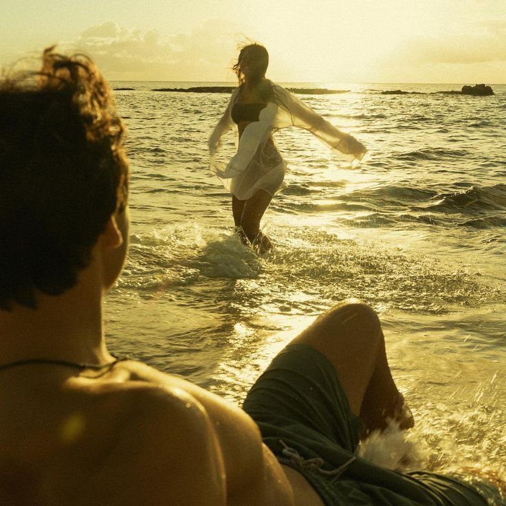 two people are in the water at sunset