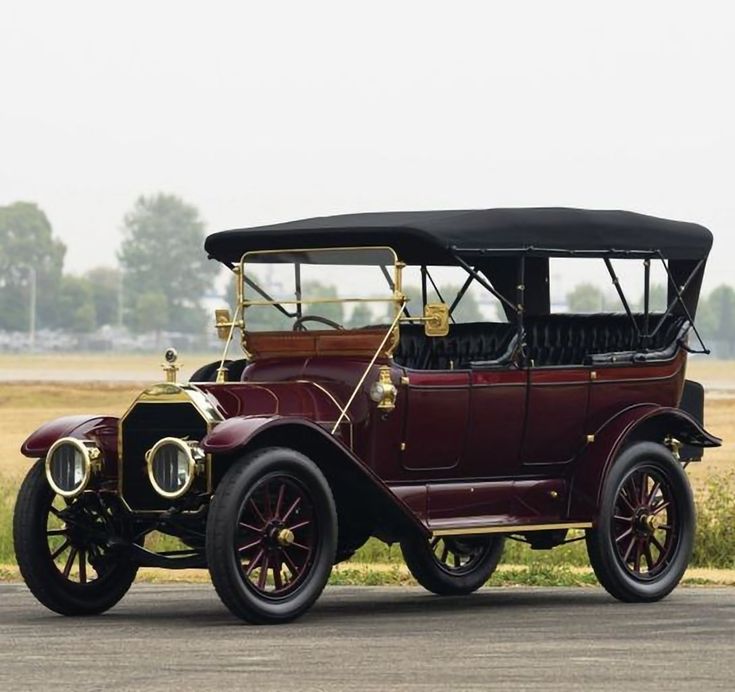 an antique car is parked on the side of the road in front of some grass