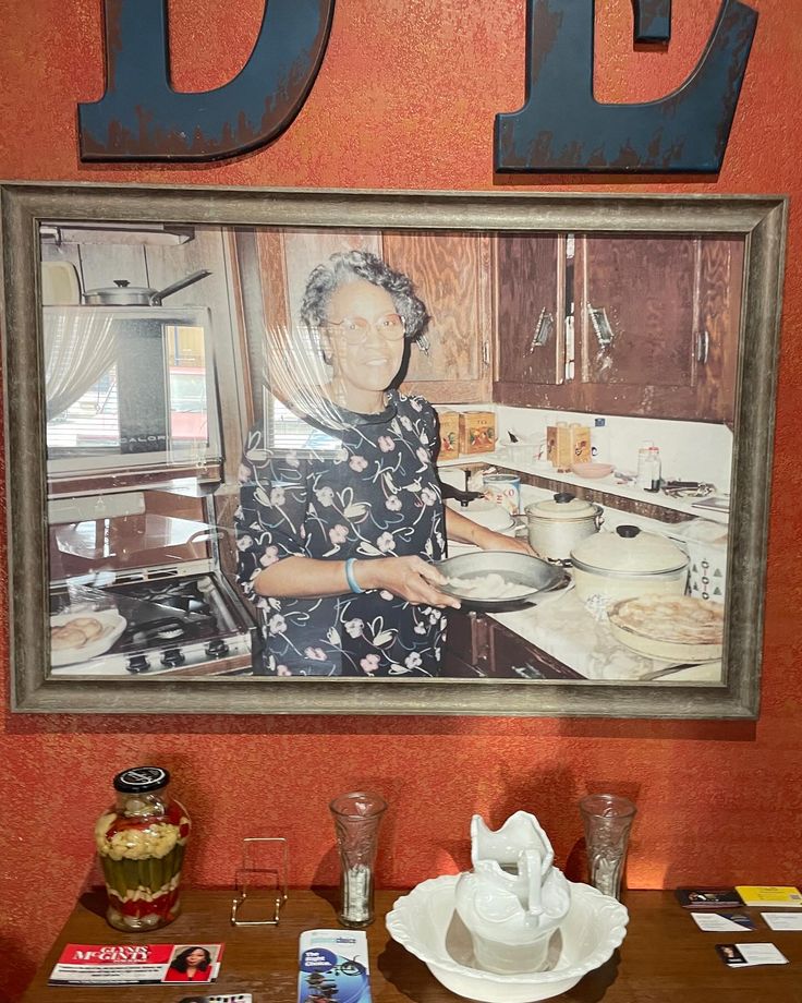 an old woman is cooking in the kitchen with letters on the wall above her and below her