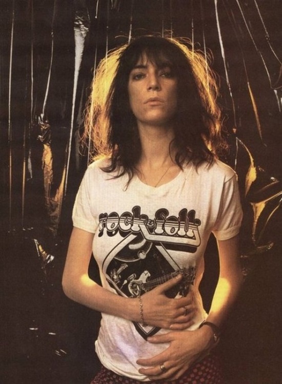 a woman with long hair standing in front of a motorcycle wearing a t - shirt