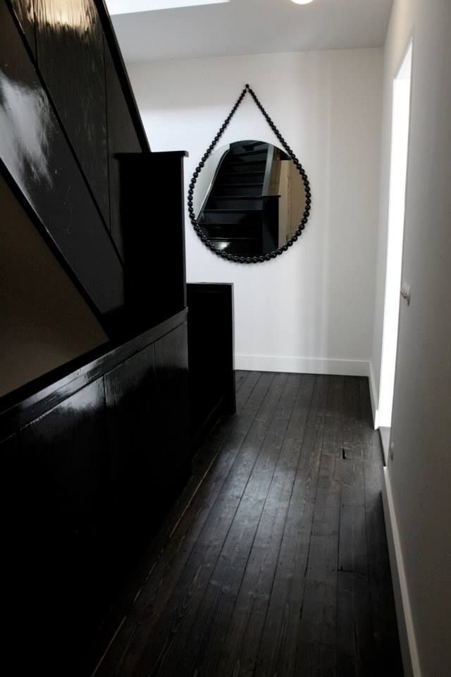 an empty hallway with black furniture and a mirror hanging on the wall next to it