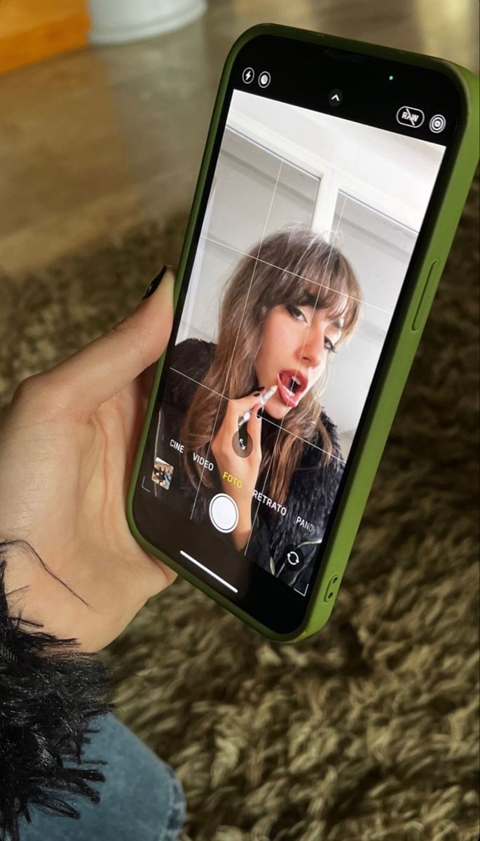 a woman holding up her cell phone to take a selfie with the screen open