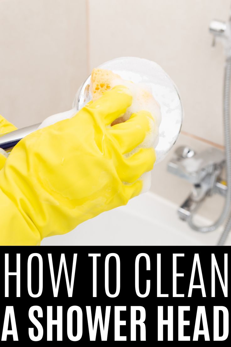 a person in yellow gloves cleaning a shower head