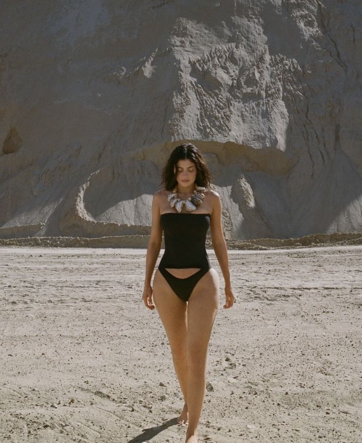 a woman in a bathing suit walking on the beach