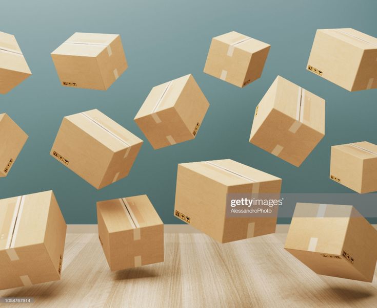 many cardboard boxes flying in the air on a wooden floor with blue wall behind them