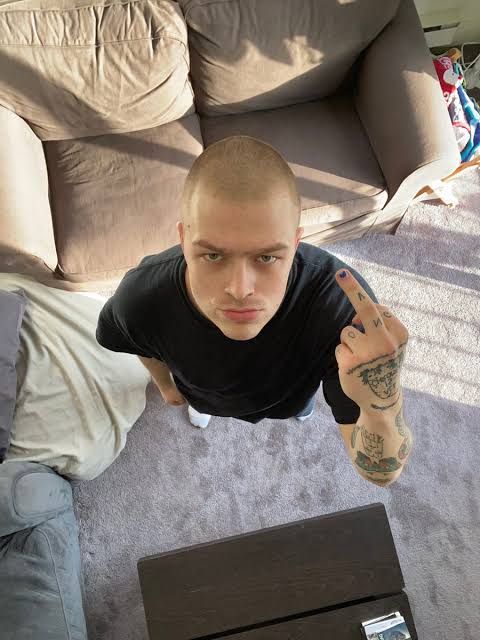 a man is sitting on the floor in front of a laptop and pointing at something