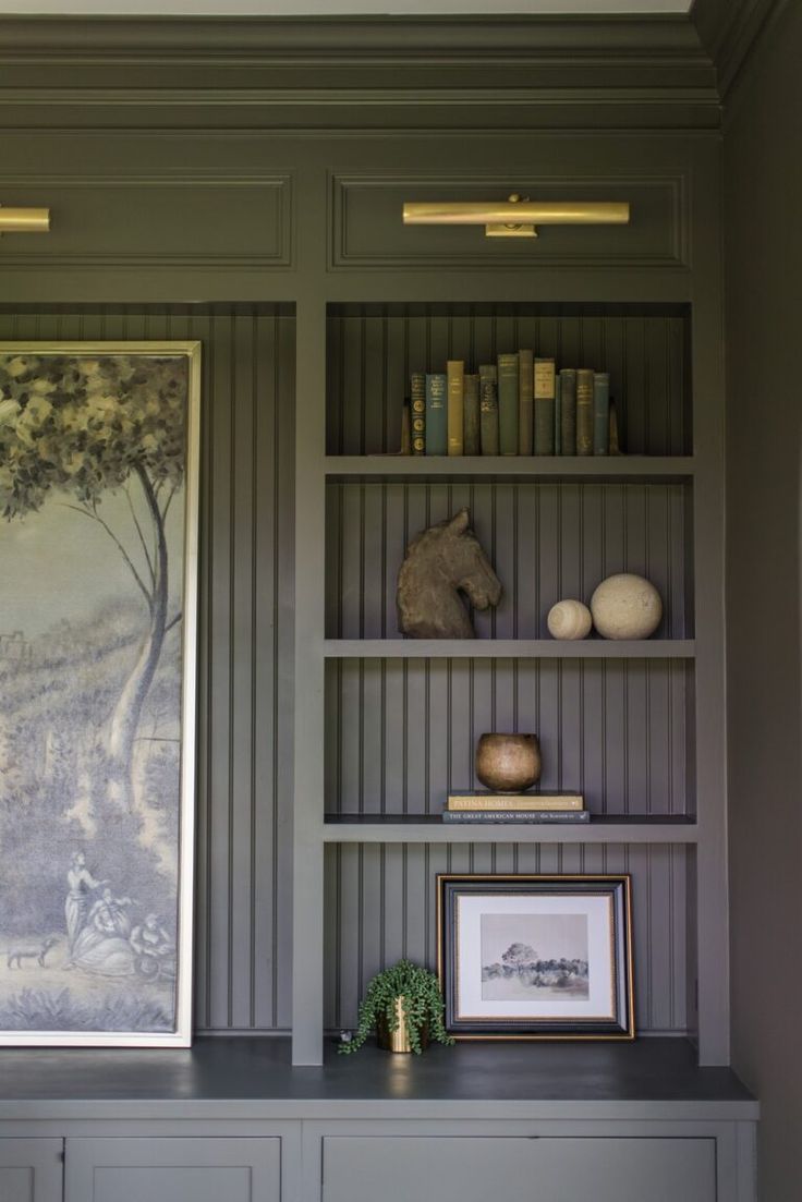 a painting on the wall next to bookshelves with pictures and other items in it