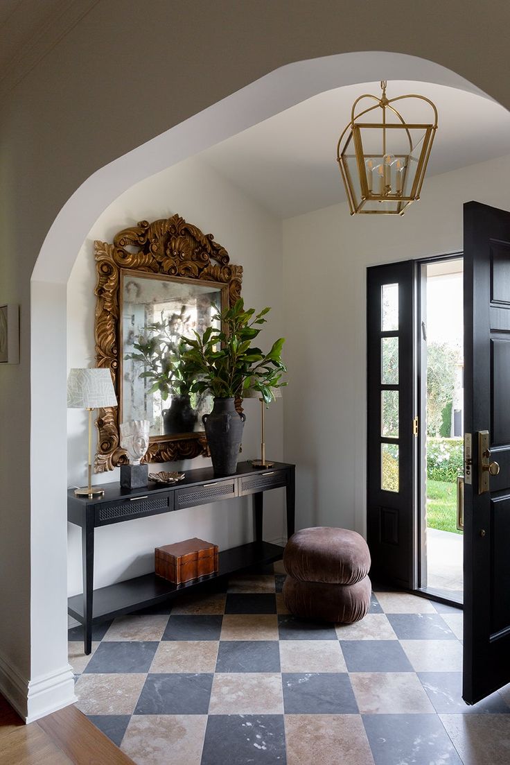 an entry way with a mirror, stool and potted plant on the table in front of it