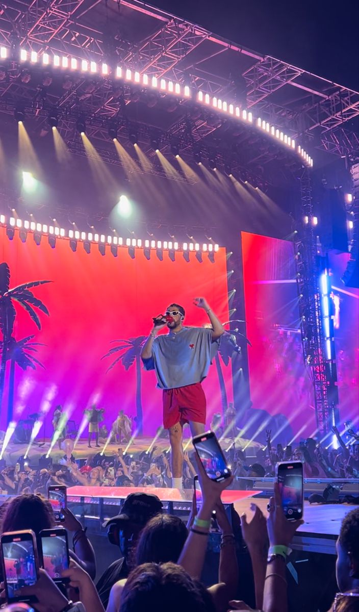 a man standing on top of a stage holding a cell phone in front of him