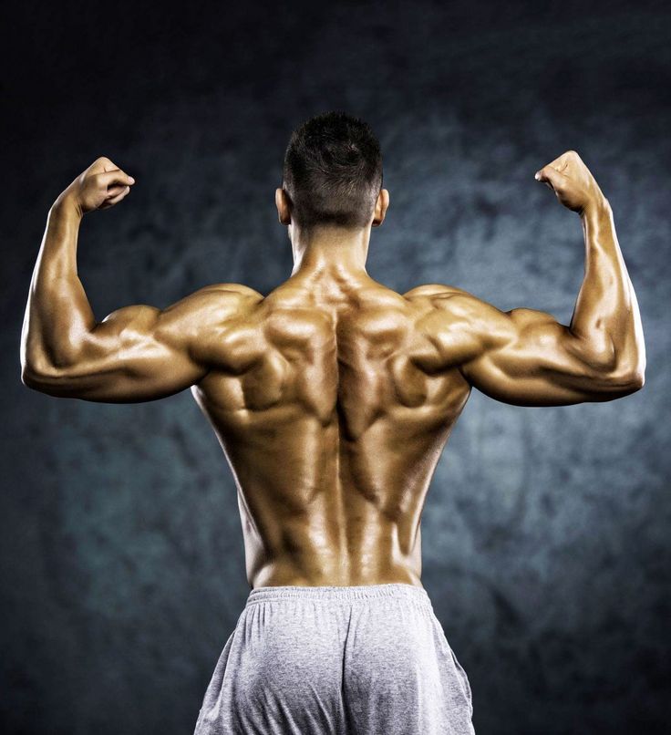 a man flexing his muscles in front of a dark background