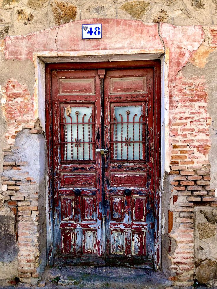 an old red door with two windows on the side of a brick building in italy