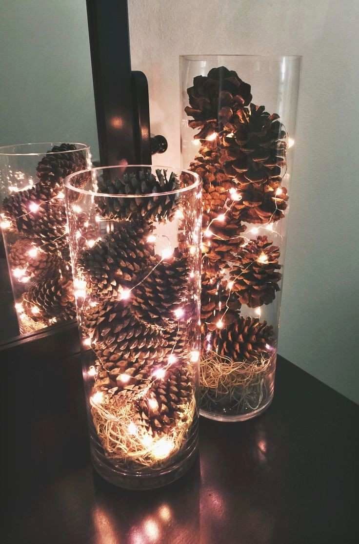 two glass vases filled with pine cones on top of a table