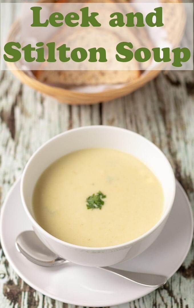 a white bowl filled with soup sitting on top of a saucer next to bread