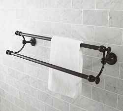 two towels are hanging on the wall next to a towel rack in a tiled bathroom