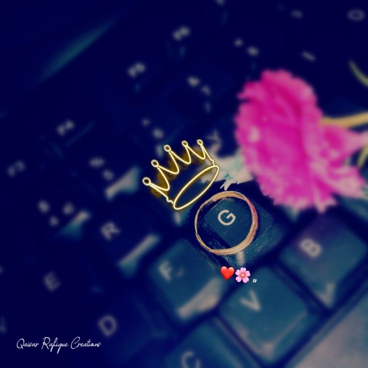 a close up of a keyboard with a crown on it's head and a pink flower