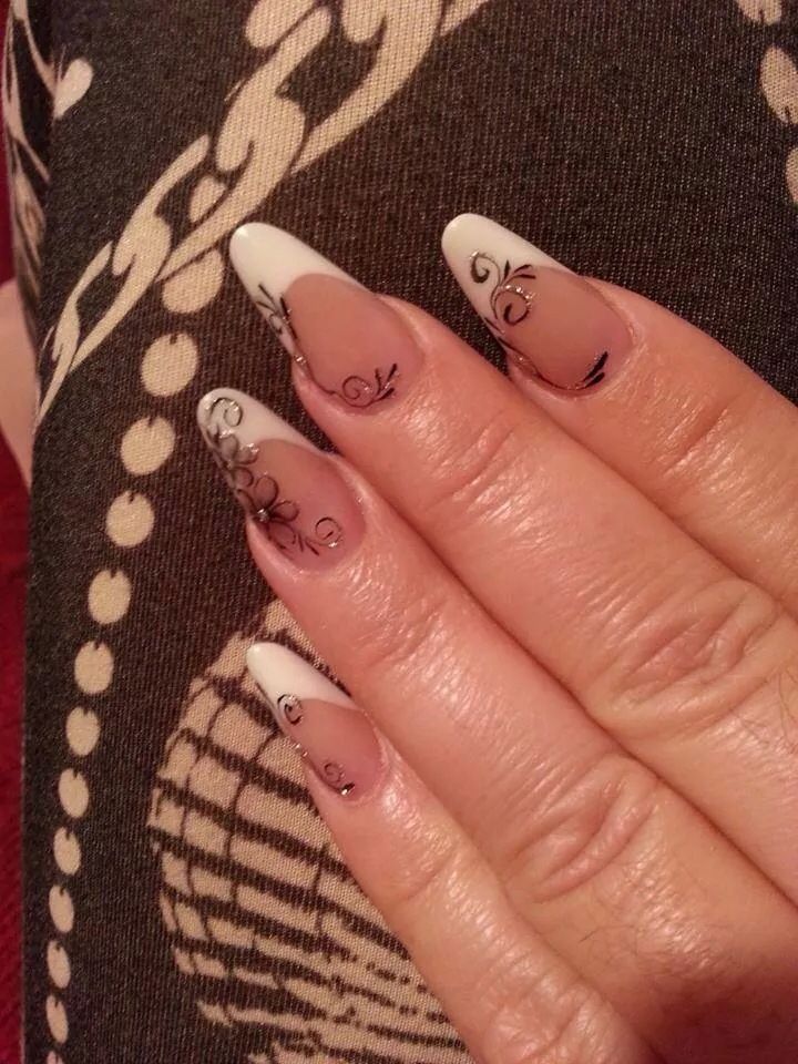 a woman's hand with white and black nail designs on it, holding onto her nails