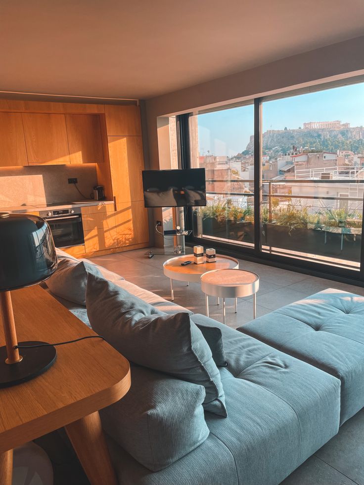 a living room filled with furniture and a large window overlooking the cityscape in the distance