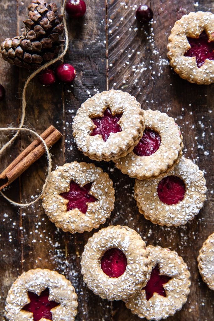 small cookies with cranberry filling on a wooden table next to cinnamon sticks and a pine cone