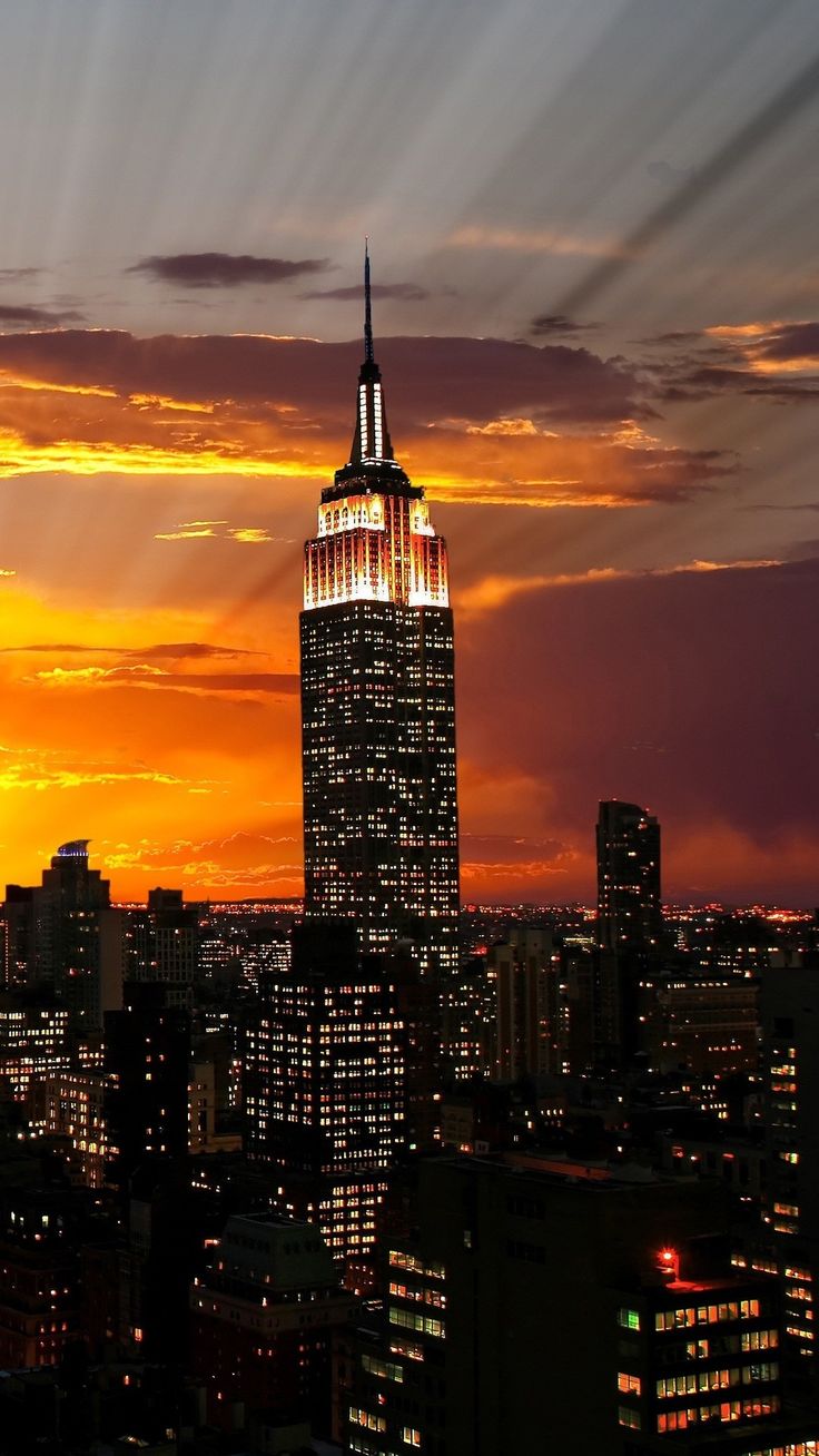 the empire building is lit up at night in new york city, with its lights on