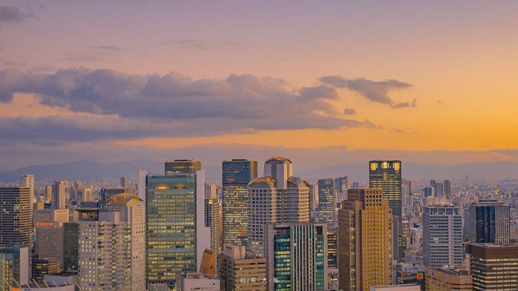 the city skyline is lit up at sunset with skyscrapers in the foreground and mountains in the background