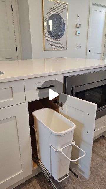 a kitchen with white cabinets and an open trash can