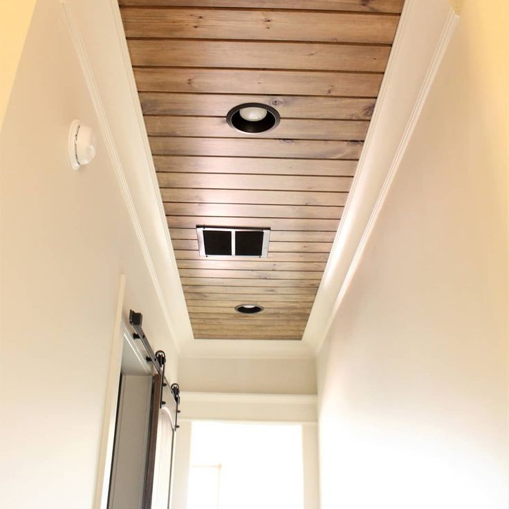 the ceiling in this bathroom is made out of wood and has a light fixture on it