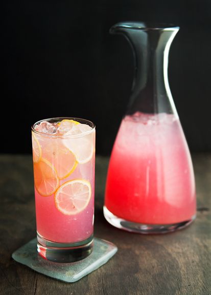 a pitcher and a glass filled with pink lemonade