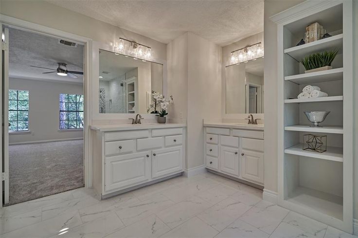 a large bathroom with two sinks and white cabinets