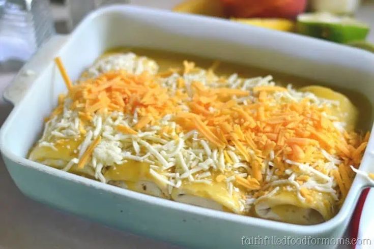 a casserole dish with cheese on top and other food items in the background