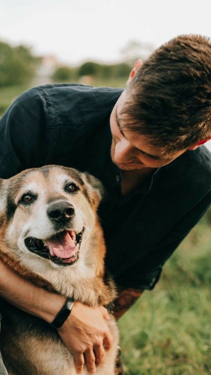 a man is hugging his dog outside in the grass