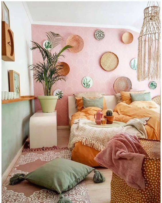 a bedroom with pink walls and lots of pillows on the floor, plants in pots