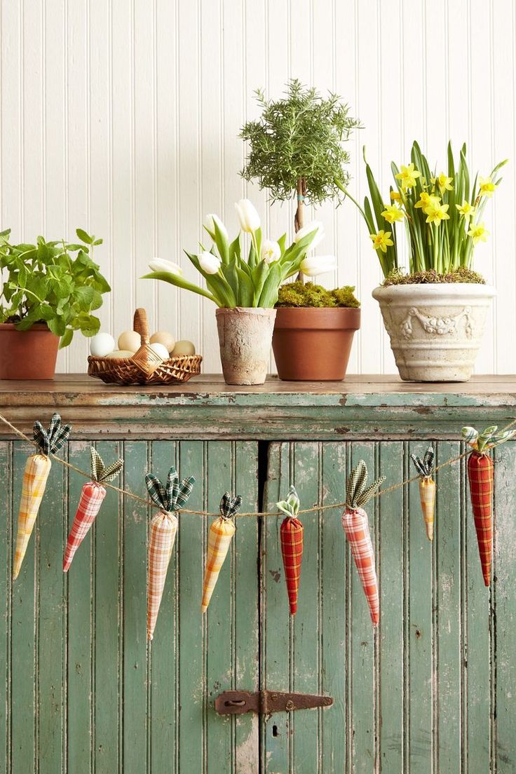 some carrots are hanging from a line on a shelf next to potted plants