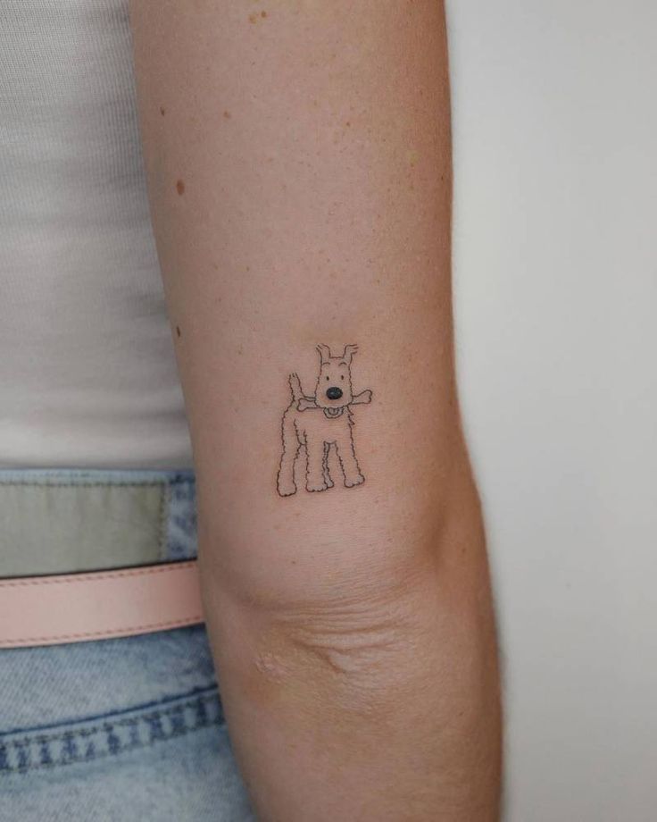 a woman's arm with a small tattoo of a dog on the left side of her arm