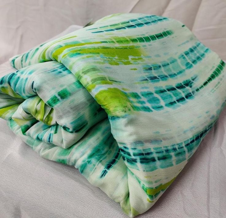 a green and white tie dyed pillow on a bed