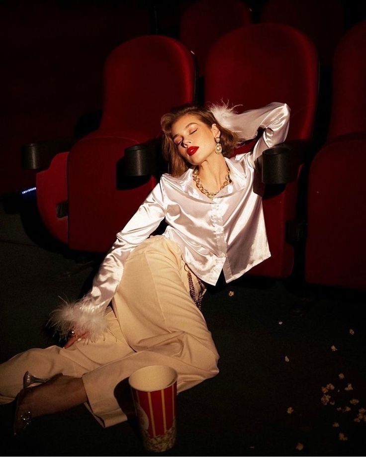 a woman sitting on the floor in front of a red chair with her eyes closed