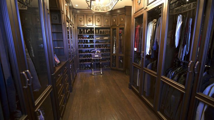 a walk in closet filled with lots of clothes and other items on shelves next to a chandelier