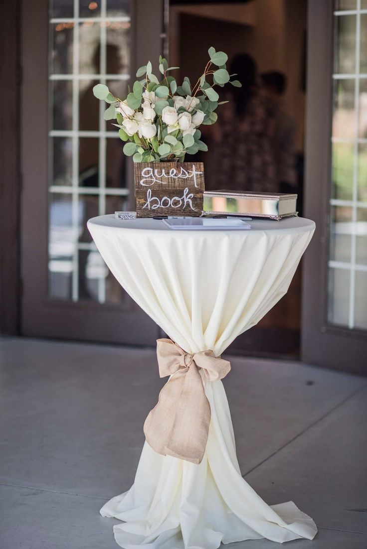 a table with a sign and flowers on it that says guest book sitting on top of the table