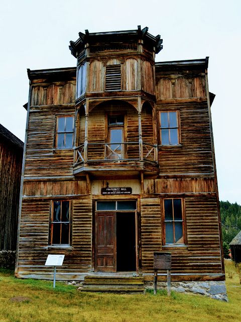 an old wooden building sitting on top of a lush green field