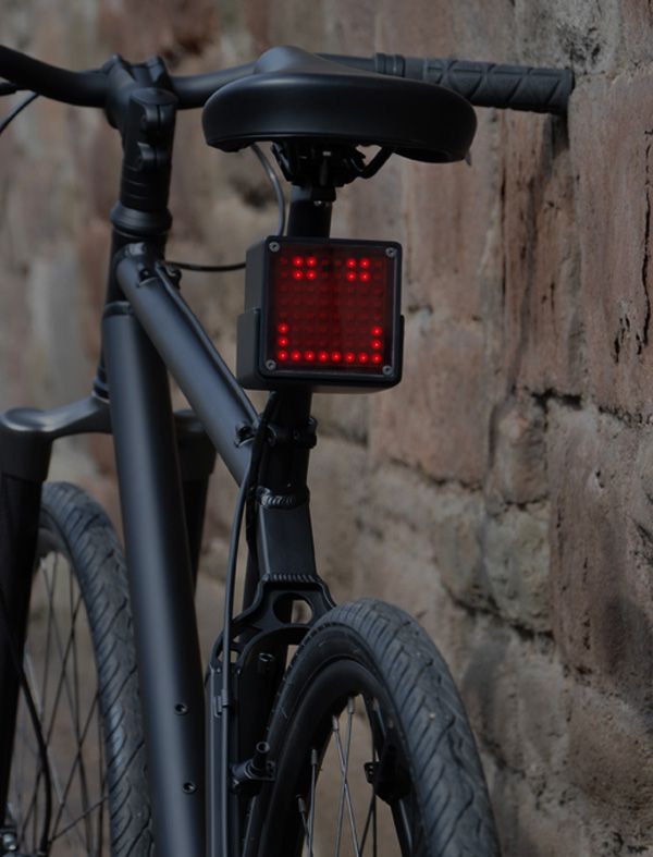 a close up of a bike parked next to a brick wall with a red light on it