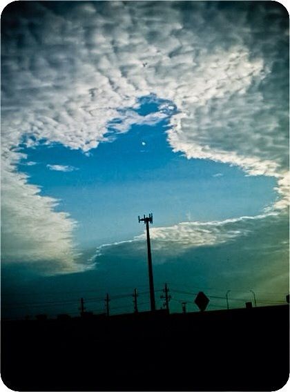 the sky is filled with clouds and street signs