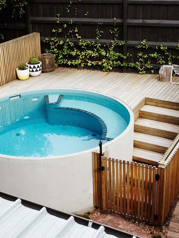 an above ground swimming pool with steps leading up to the decking area and wooden fence surrounding it