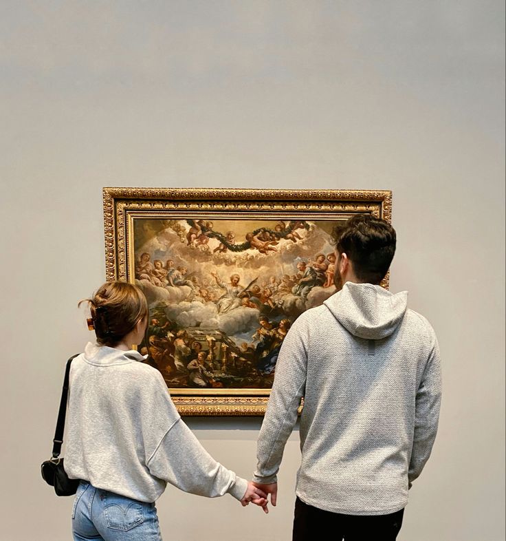 two people holding hands in front of a painting