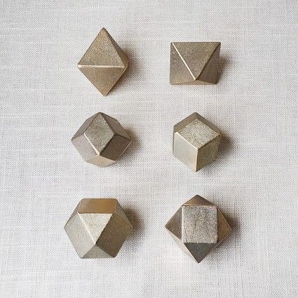 four different shapes and sizes of metal objects on a white tablecloth with linens